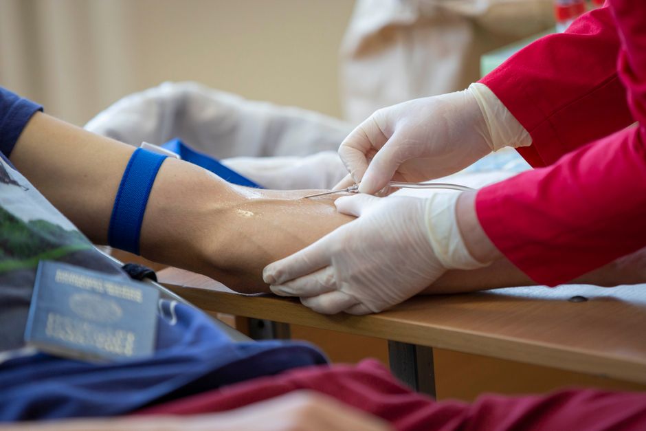 A person donating blood at a clinic while a nurse monitors the donation process