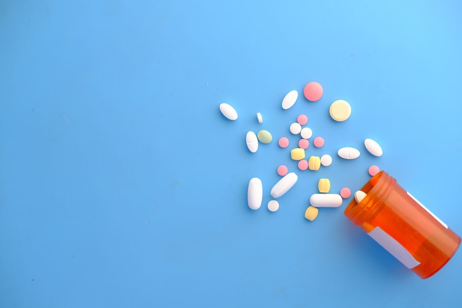 Antibiotic capsules next to an oxycodone pill bottle representing drug interaction concerns