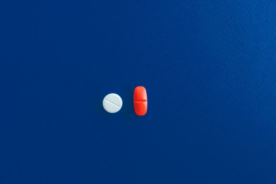 Bottle of oxycodone pills next to a sleep medication bottle on a nightstand