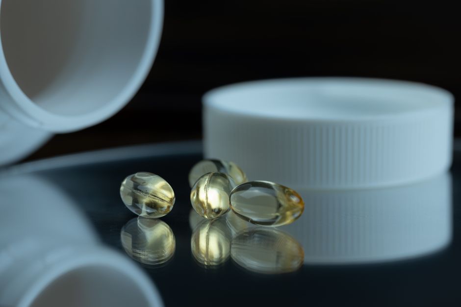 Melatonin supplement bottle and pills next to prescription oxycodone bottle on a nightstand