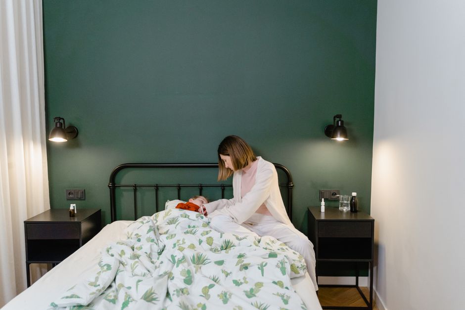 Person holding a pill bottle beside a glass of water on a nightstand at night, illustrating oxycodone nighttime dosing
