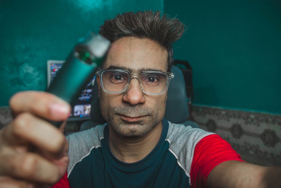 Person holding a vape device next to a bottle of oxycodone pills, illustrating nicotine and medication interaction concerns