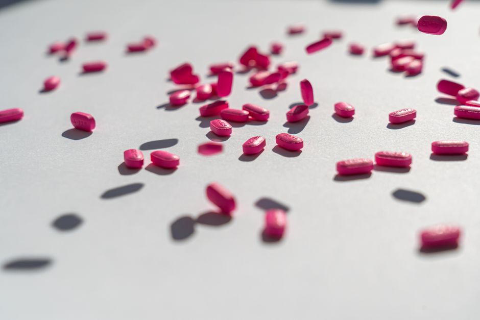 Person holding allergy medicine tablets next to a prescription oxycodone bottle