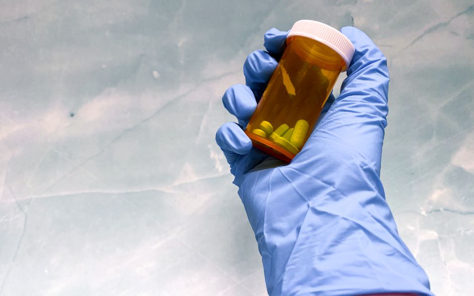Pill organizer and oxycodone bottle on a table representing safe medication use at home