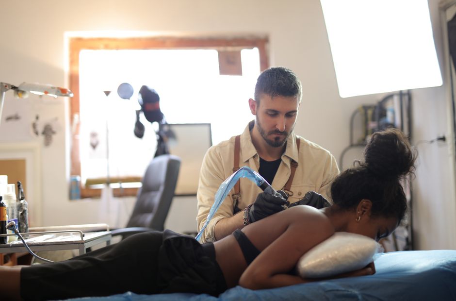 Tattoo artist working on a client's arm in a studio setting