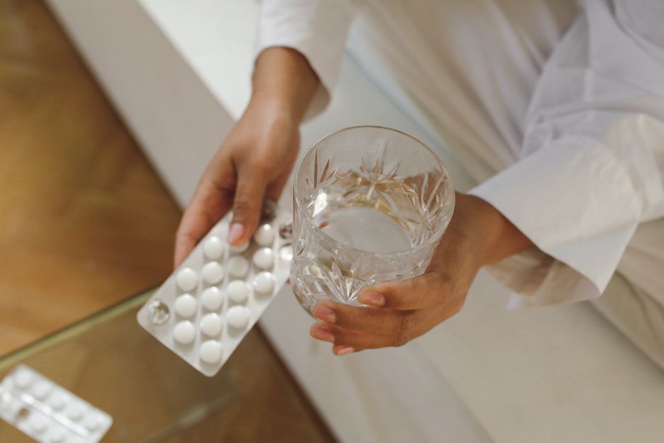 Hydrocodone pills next to a glass of alcohol illustrating the risks of mixing the two substances
